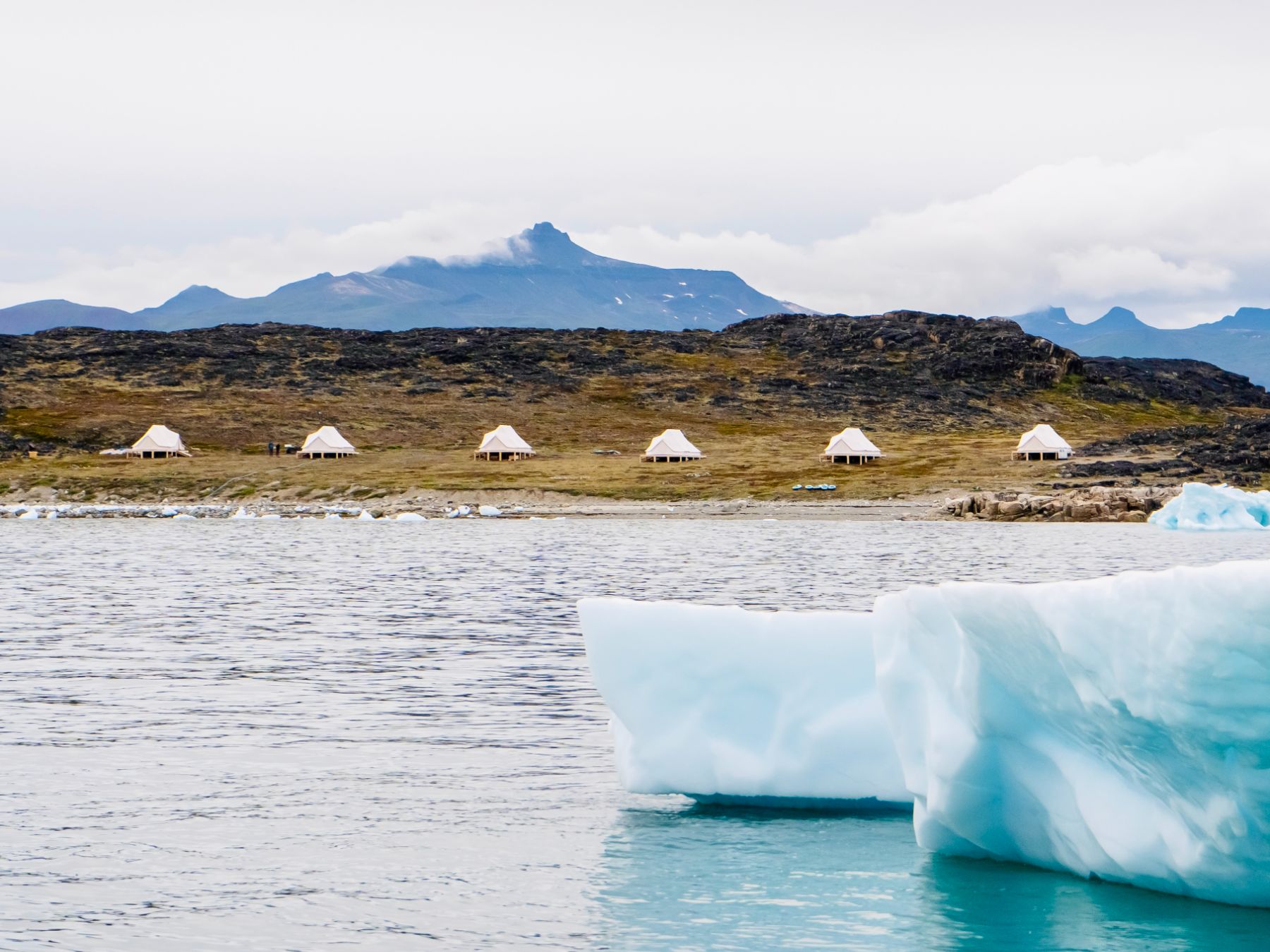 Icebergs in Disko Bay Greenland with a distant view of luxury Camp Saqqaq