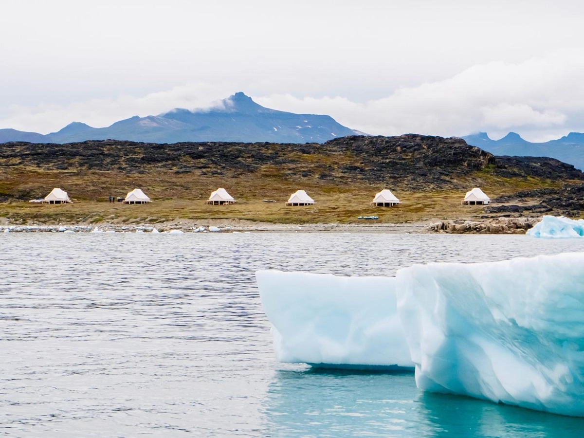 Icebergs in Disko Bay Greenland with a distant view of luxury Camp Saqqaq