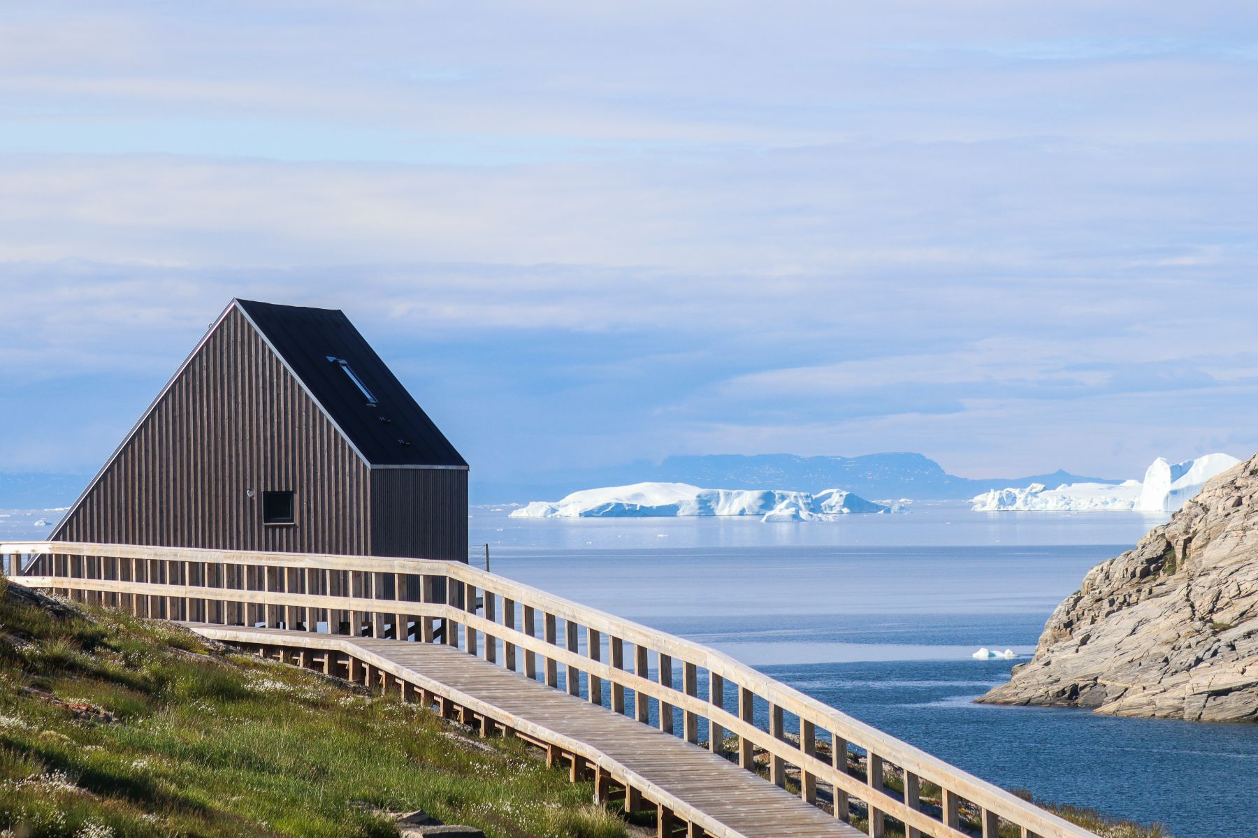 Boardwalk and bungalow at Ilimanaq Lodge Greenland looking out to icebergs in Disko Bay