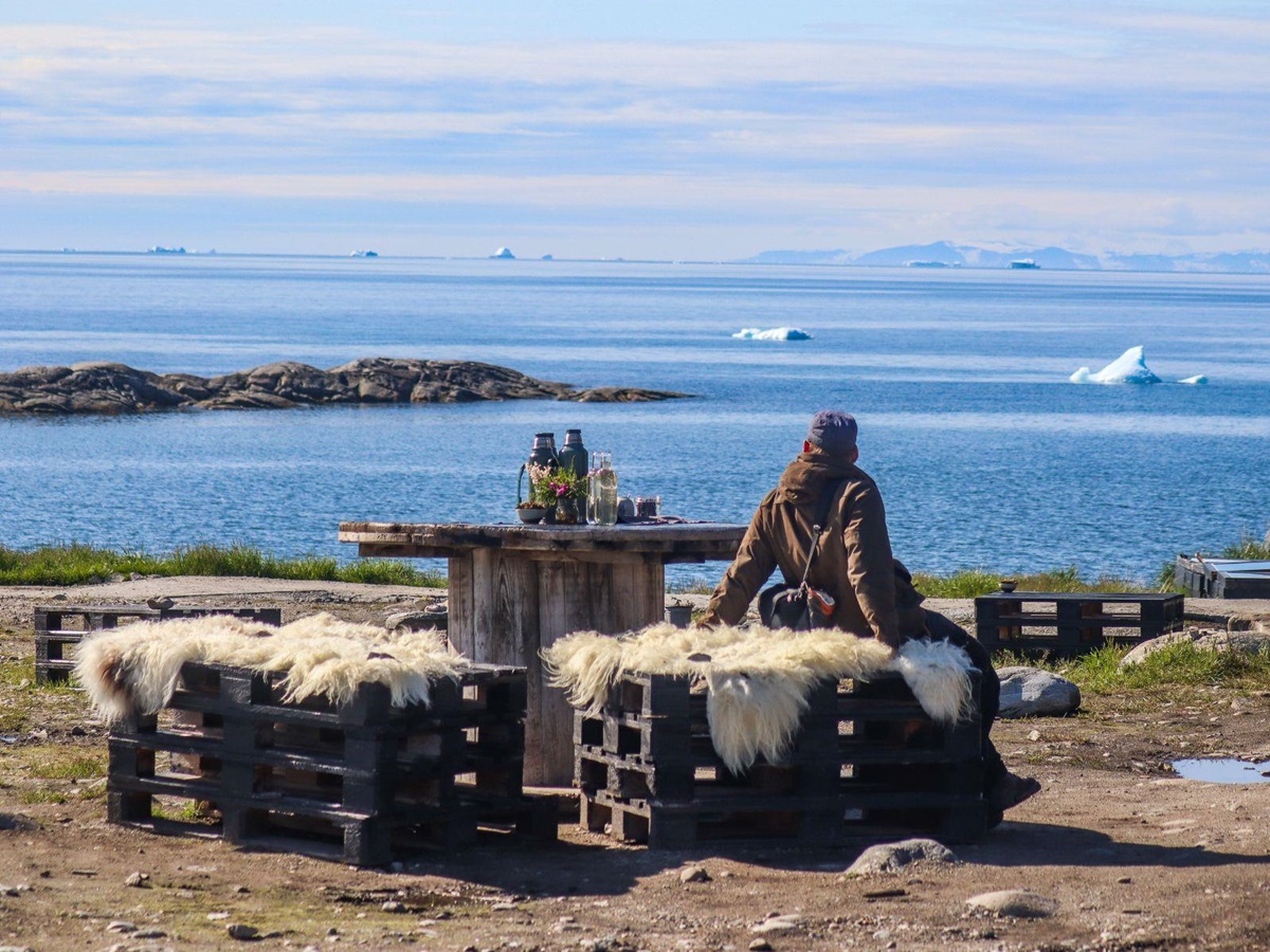 Guest at Ilimanaq Lodge Greenland enjoying outdoor dining and views of Disko Bay