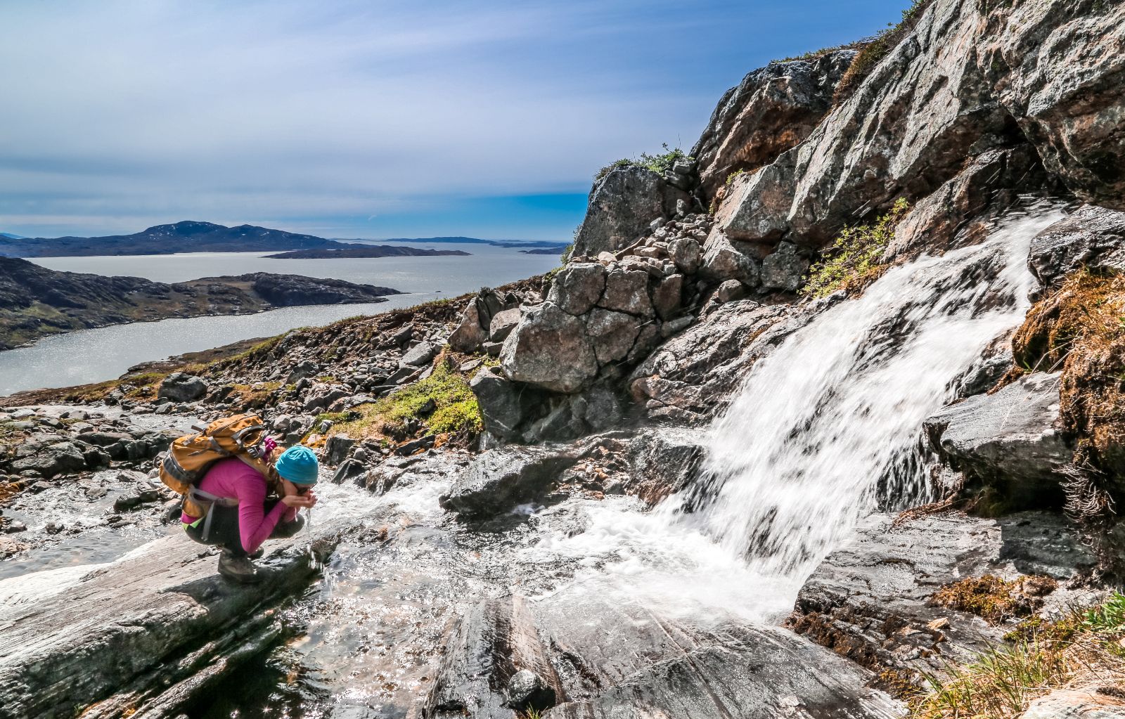 Girl drinking from a waterfall on a hike near Nuuk in Greenland
