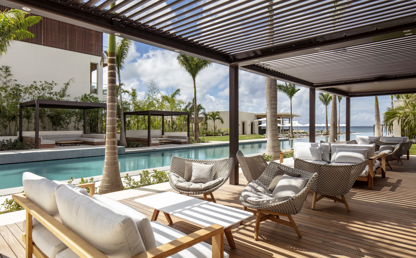 comfortable seating area with sofas and chairs in front of pool 