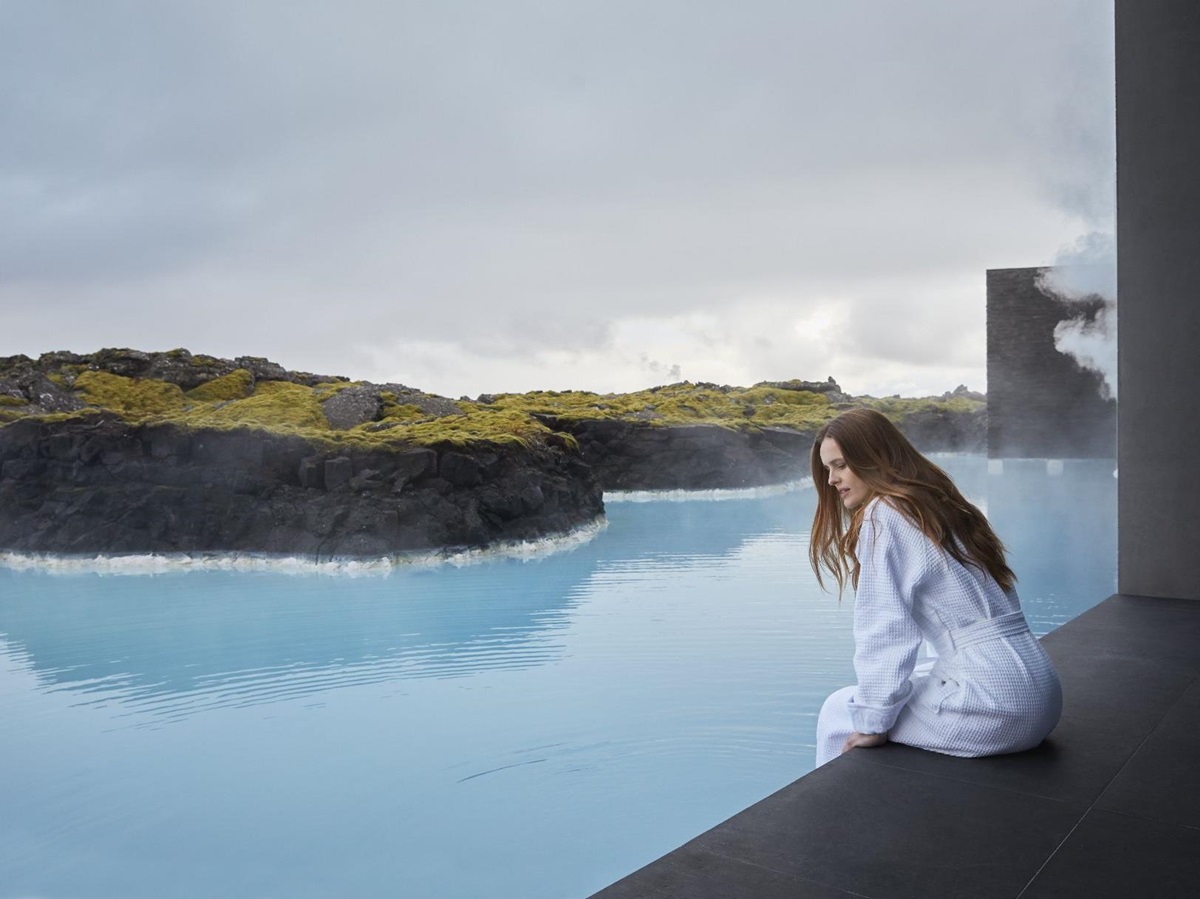 Lady dipping her feet into thermal waters from her room at The Retreat at Blue Lagoon hotel in Iceland