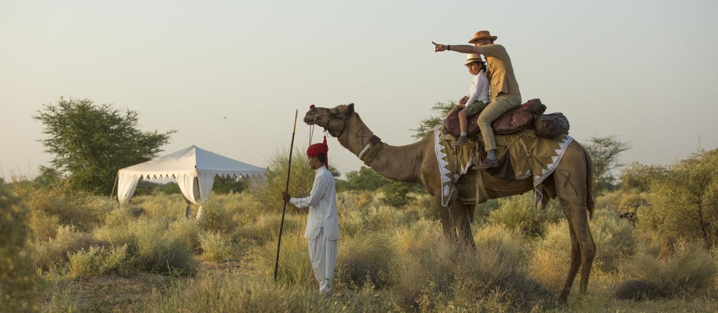 Father and child on camel safari at Sujan The Serai India