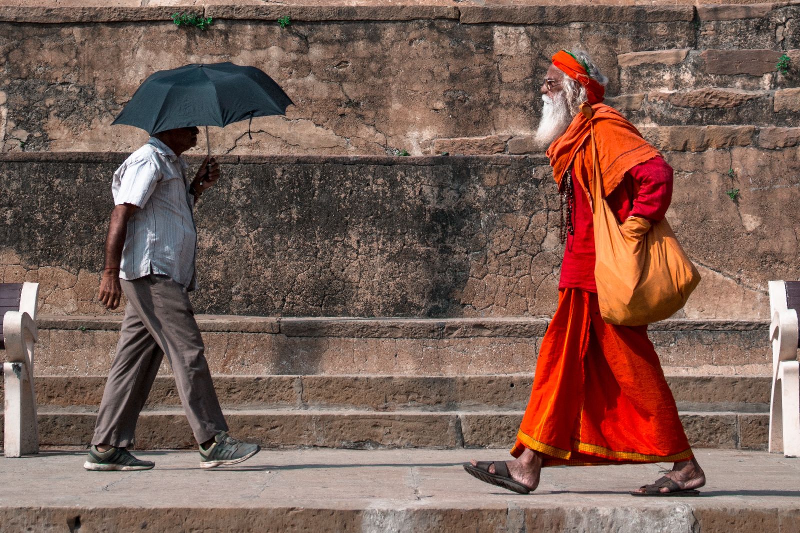 A monk in traditional dress walking down a street in India