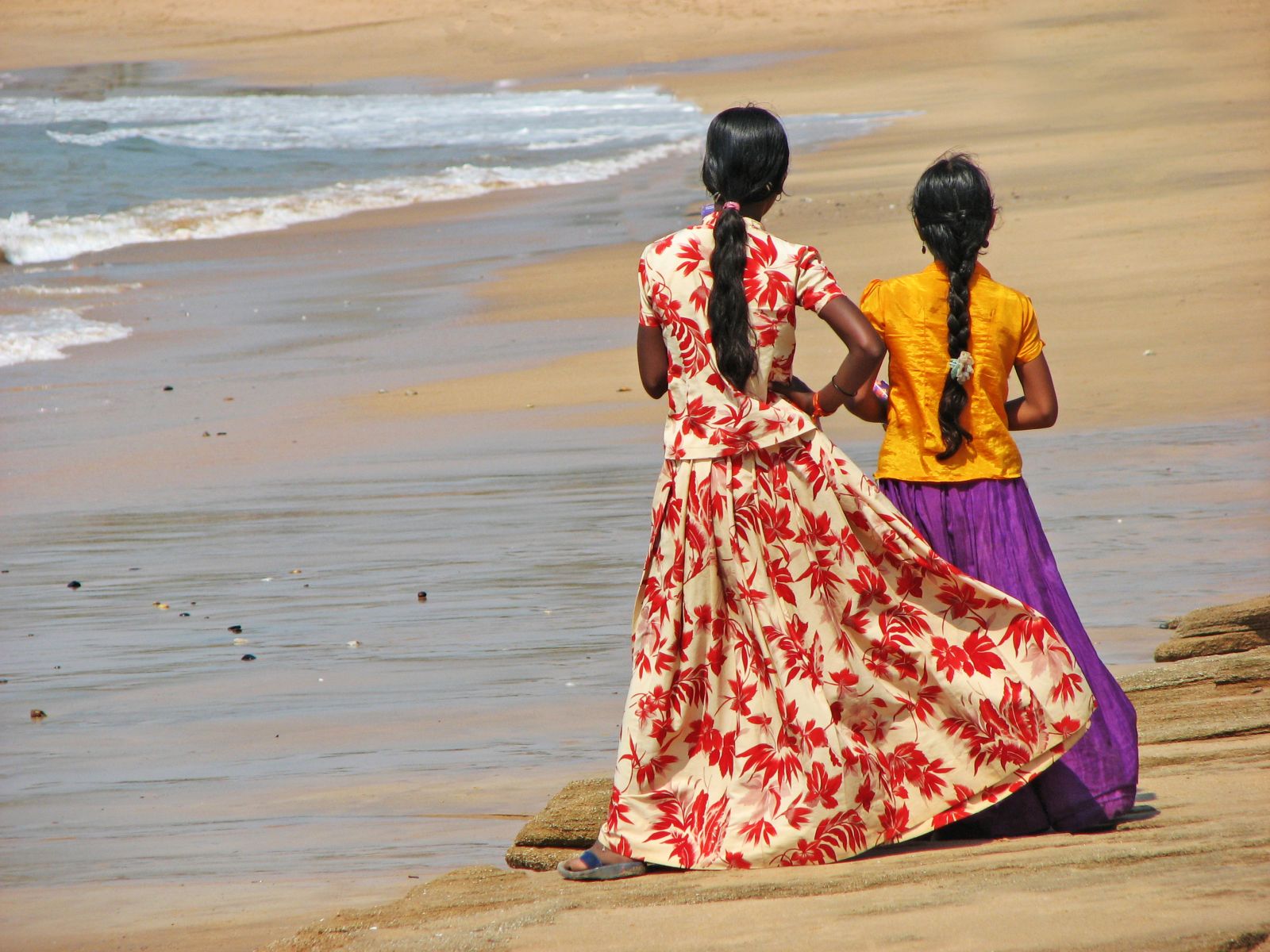 Local women in colourful dress on a beach in southern India