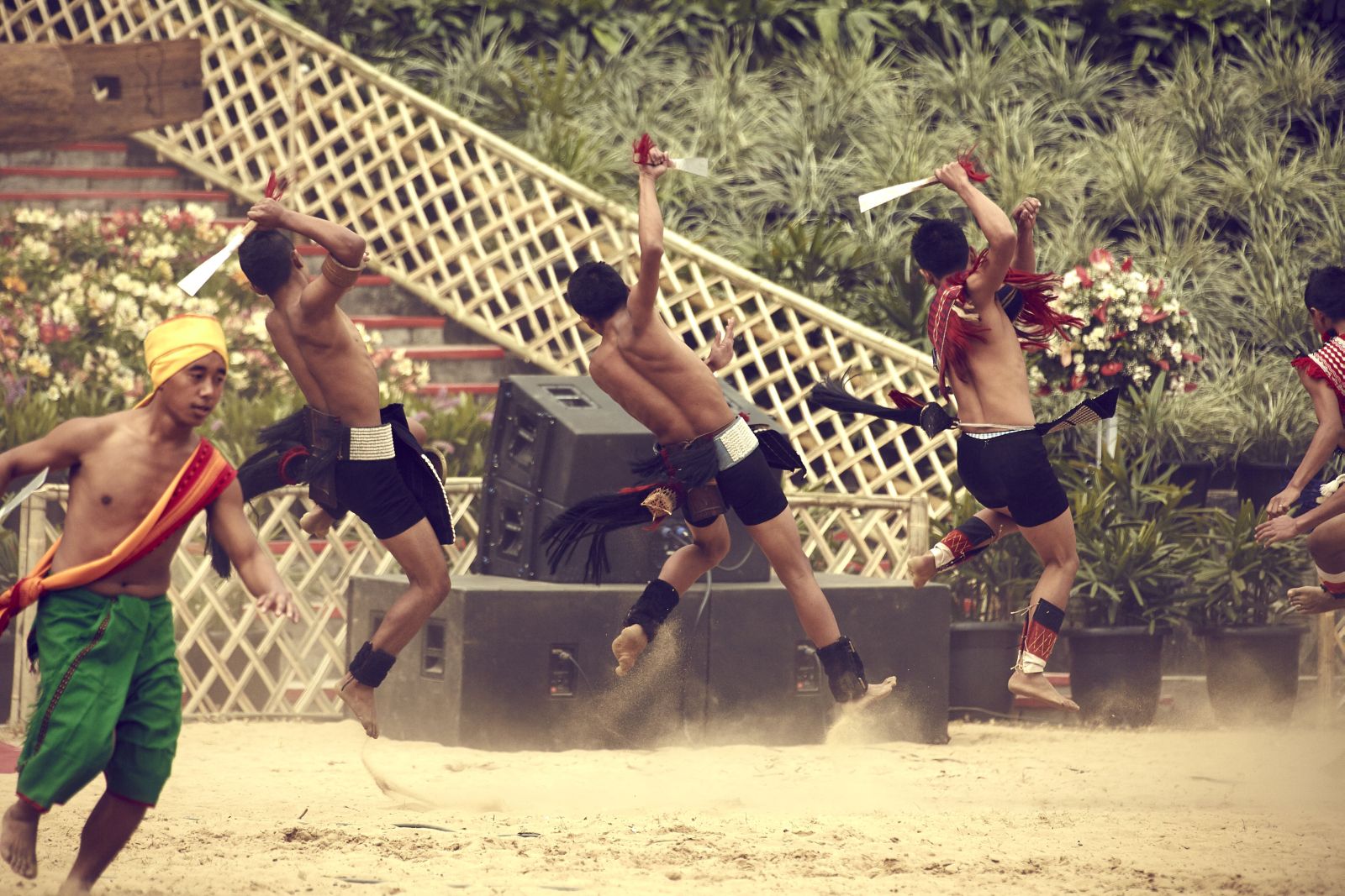 Three men from one of the Tribes of Nagaland jumping in the air whilst performing at the Hornbill Festival in North East India