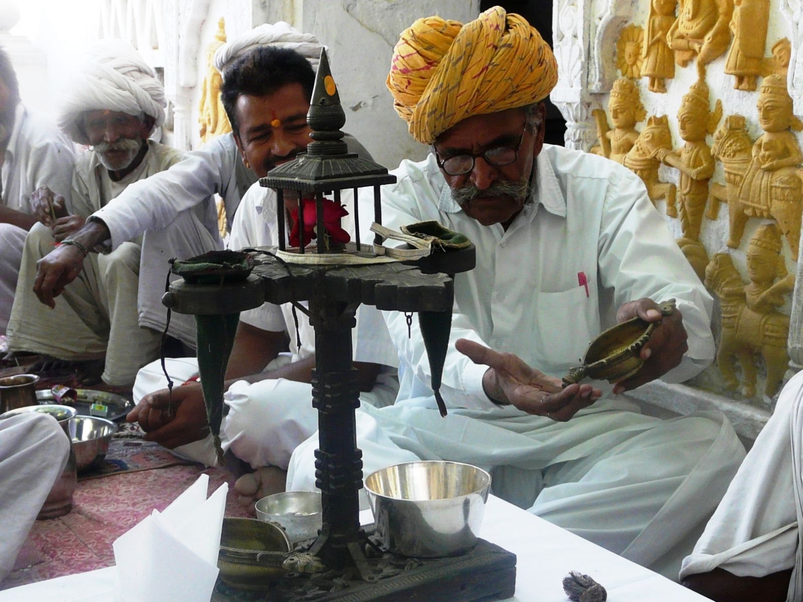 A group of Indian men sitting cross legged looking at traditional arts and craft at Rawla Narlai in India