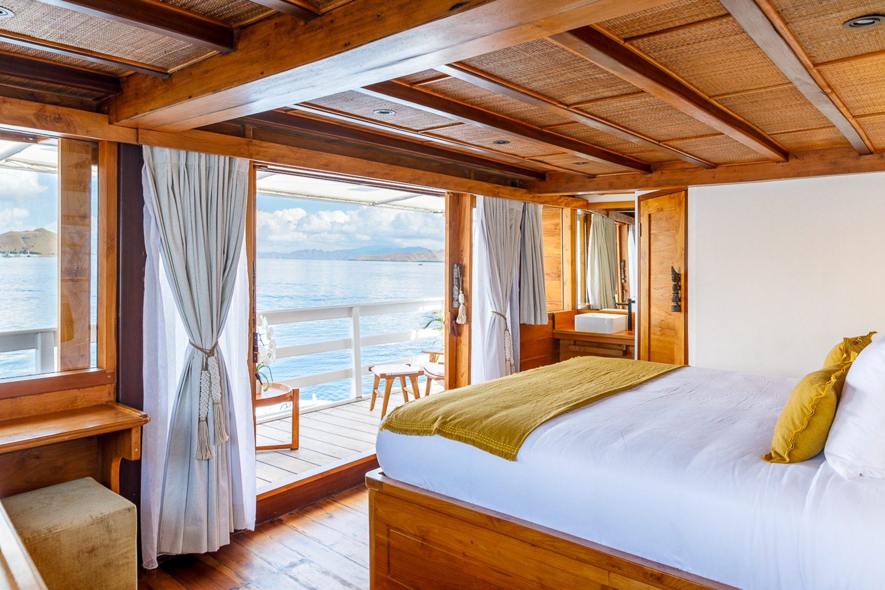 Double bed with views onboard the luxury phinisi Aliikai in Indonesia