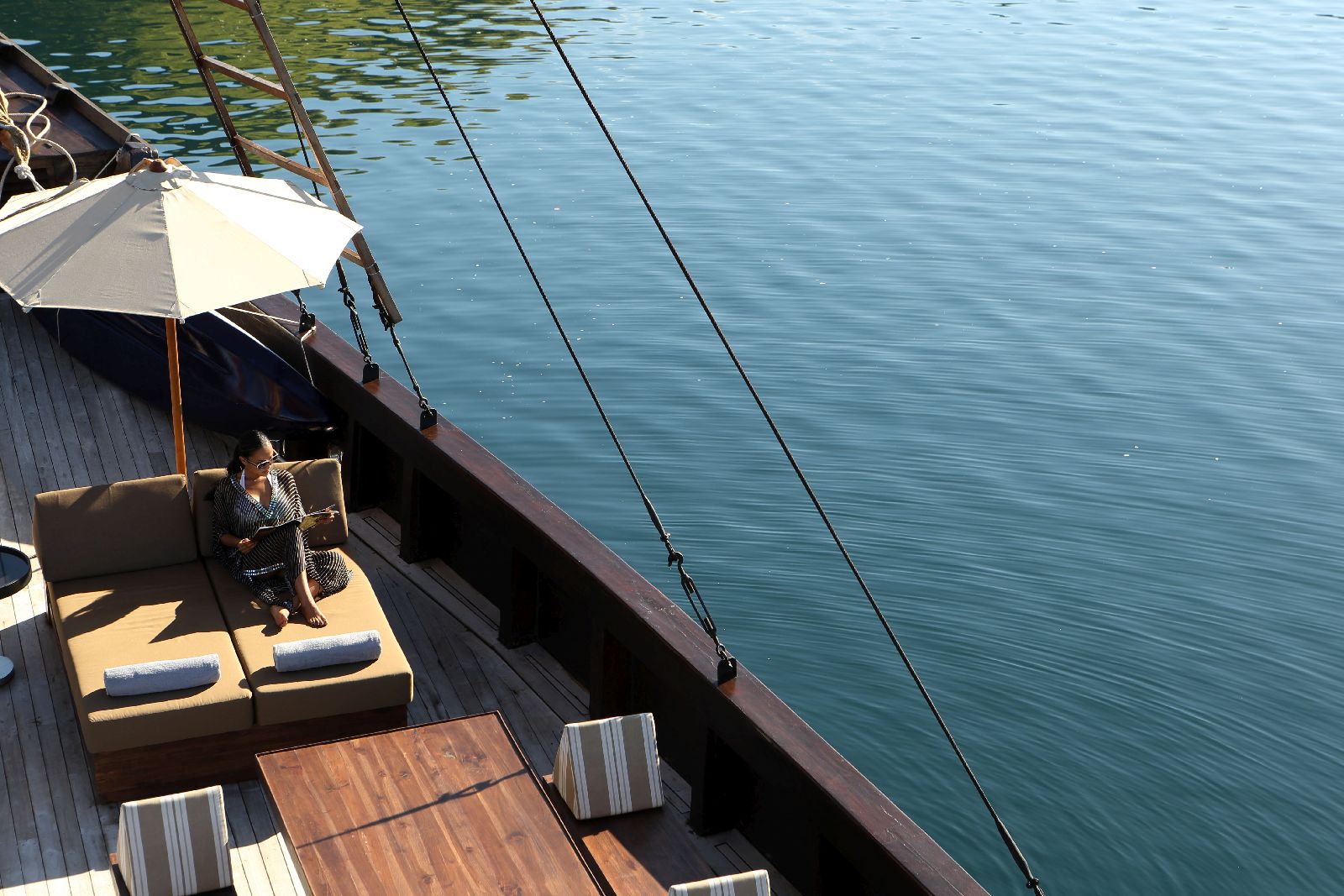 Lady relaxing on a lounger on the deck of the Alila Purnama phinisi in Indonesia