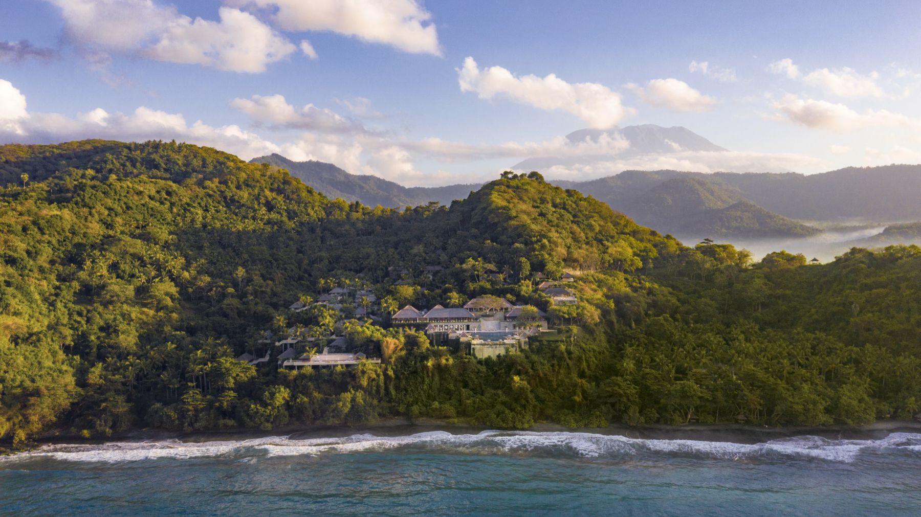 Amankila resort set against mountains and beach in Bali