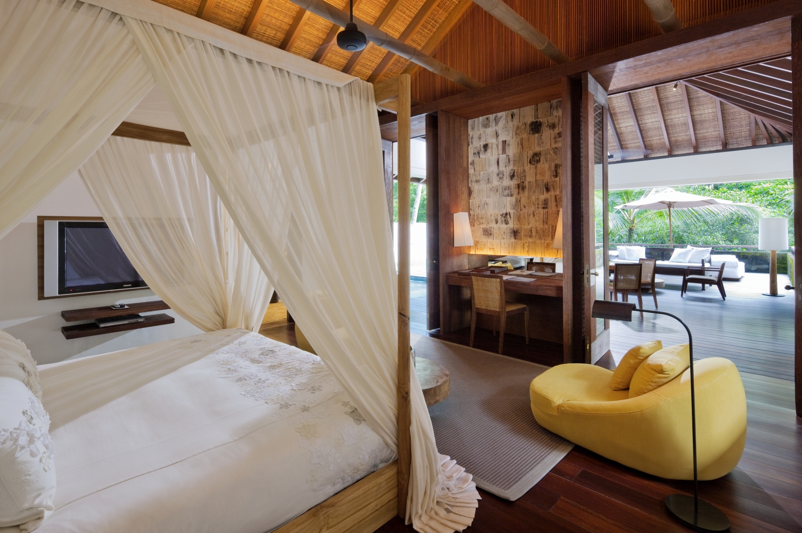 Bedroom with four poster beg and comfortable chair, as well as a private terrace