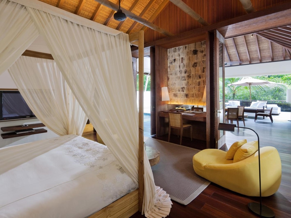 Bedroom with four poster beg and comfortable chair, as well as a private terrace