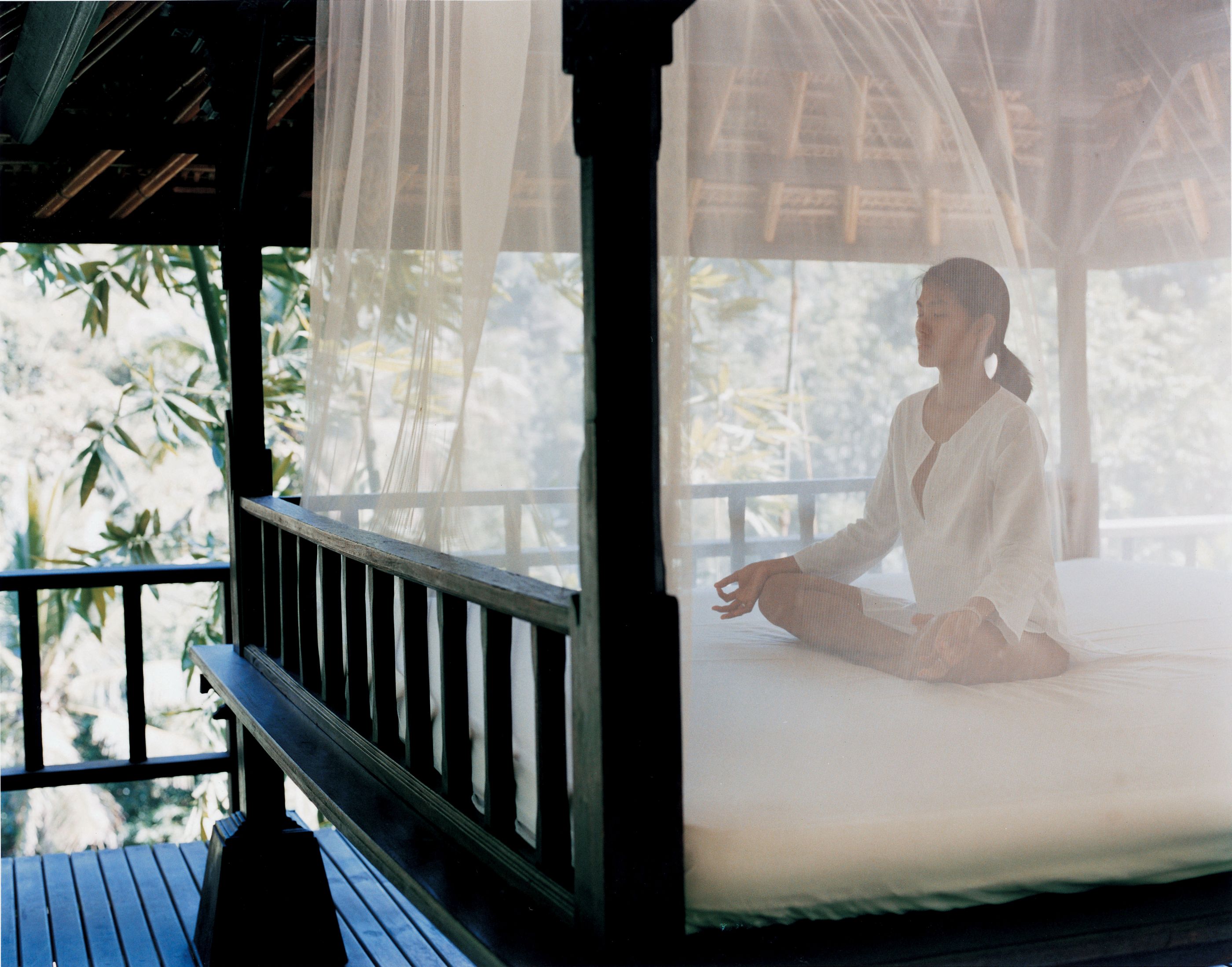 Woman meditating on a bed at Como Shambhala, Indonesia