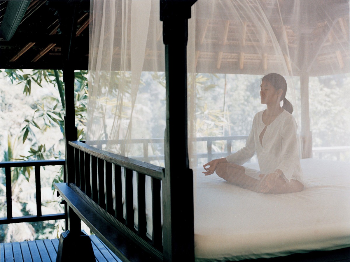 Woman meditating on a bed at Como Shambhala, Indonesia