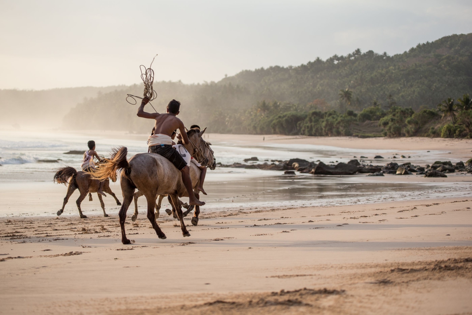 Locals riding subanese stallions on the beach at Nihi Sumba