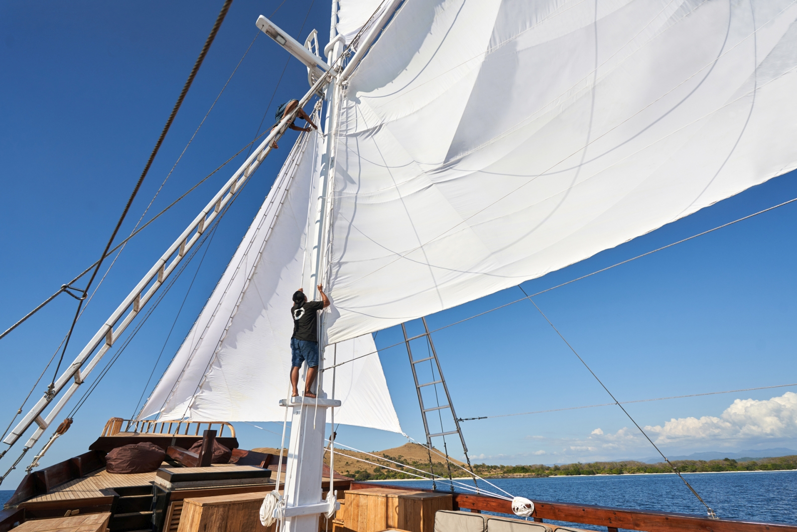 A member of crew fixing the main sail on Oracle