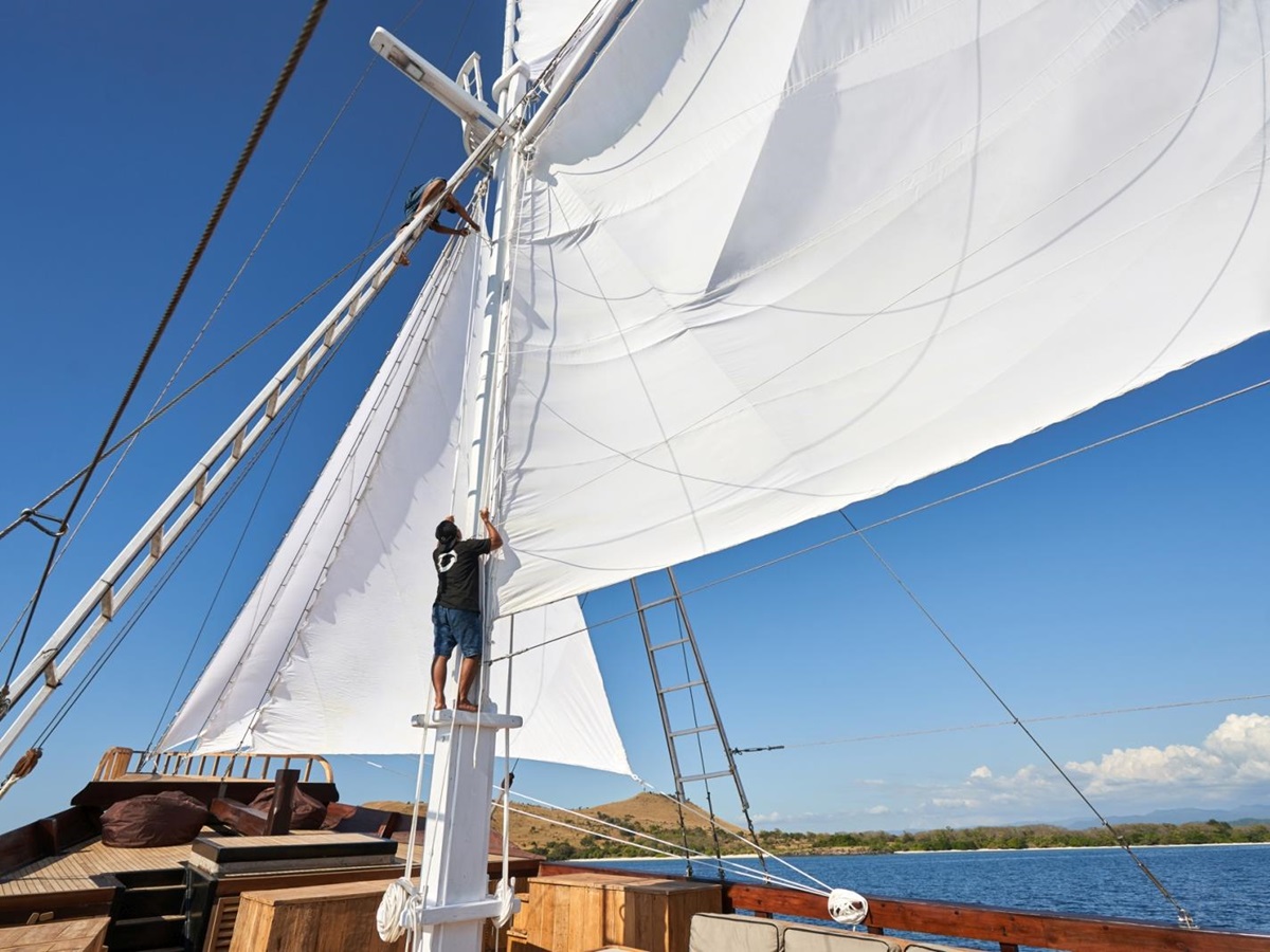 A member of crew fixing the main sail on Oracle
