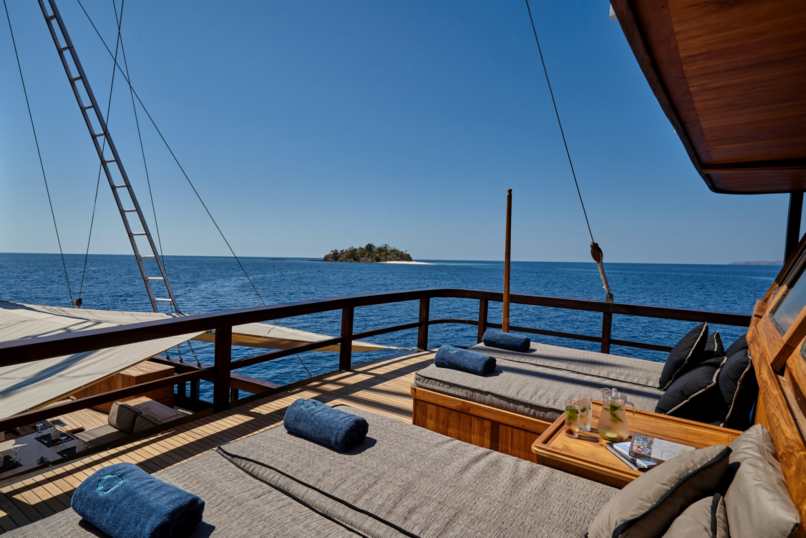 Four cushioned sun loungers on deck of Oracle