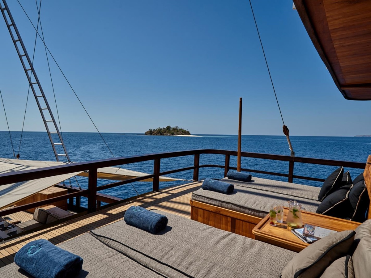 Four cushioned sun loungers on deck of Oracle