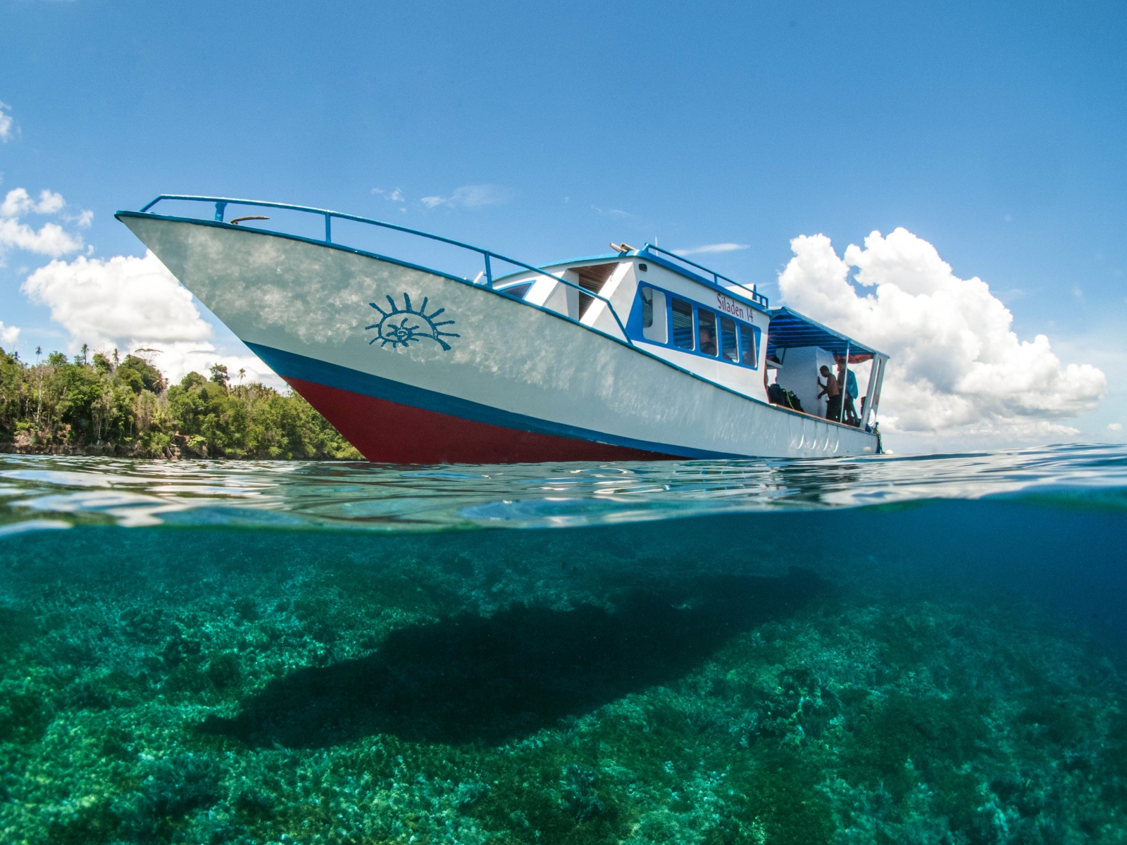 Boat at hotel Siladen in Indonesia and view under with clear blue water