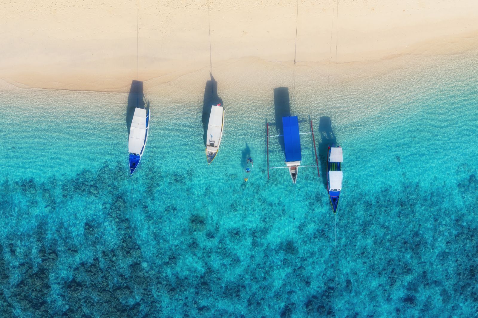 Aerial view of boats on a white sand beach on the Gili Islands in Indonesia