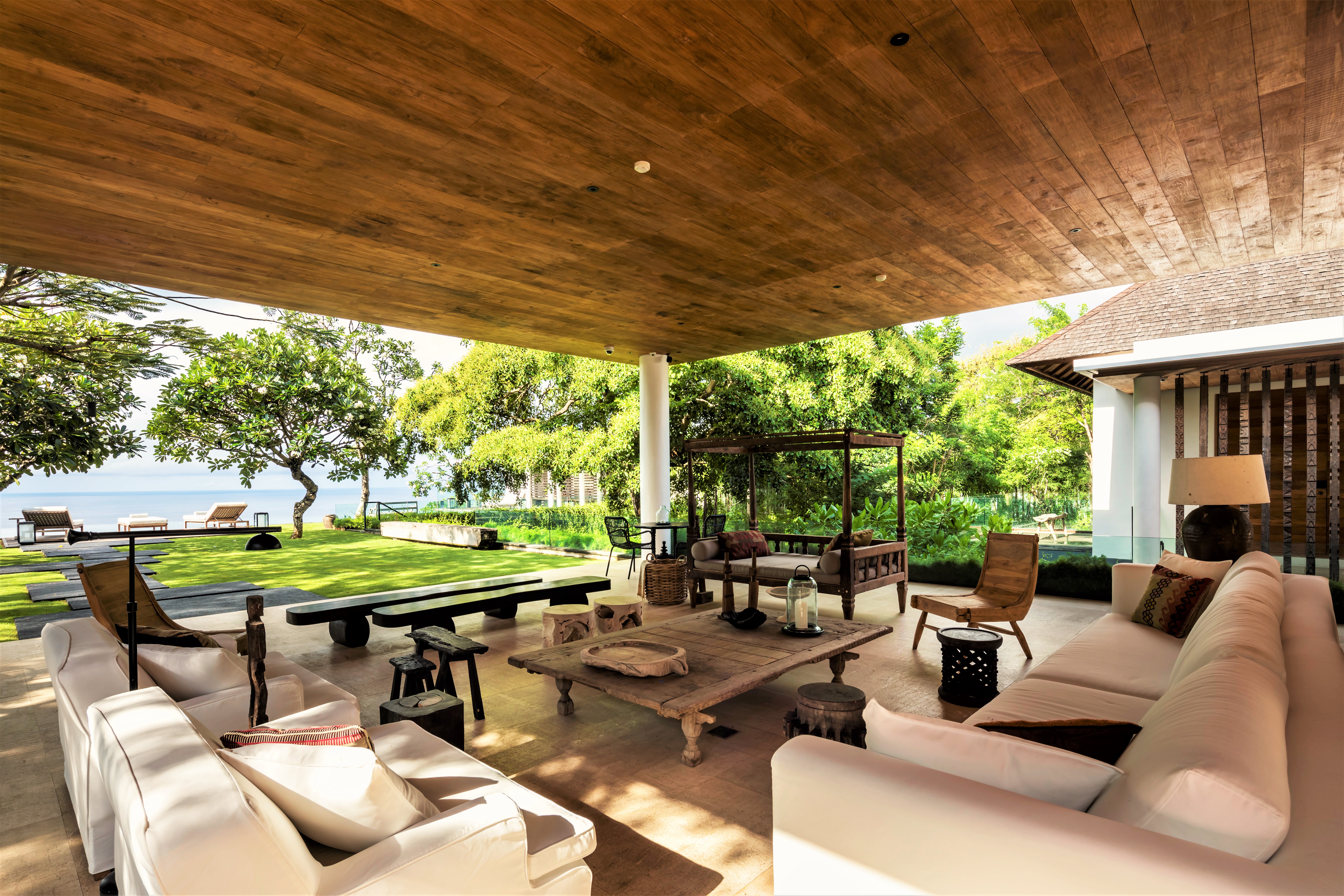 Outside seating area with wooden furniture and sofas at Uluwatu Estate, Bali