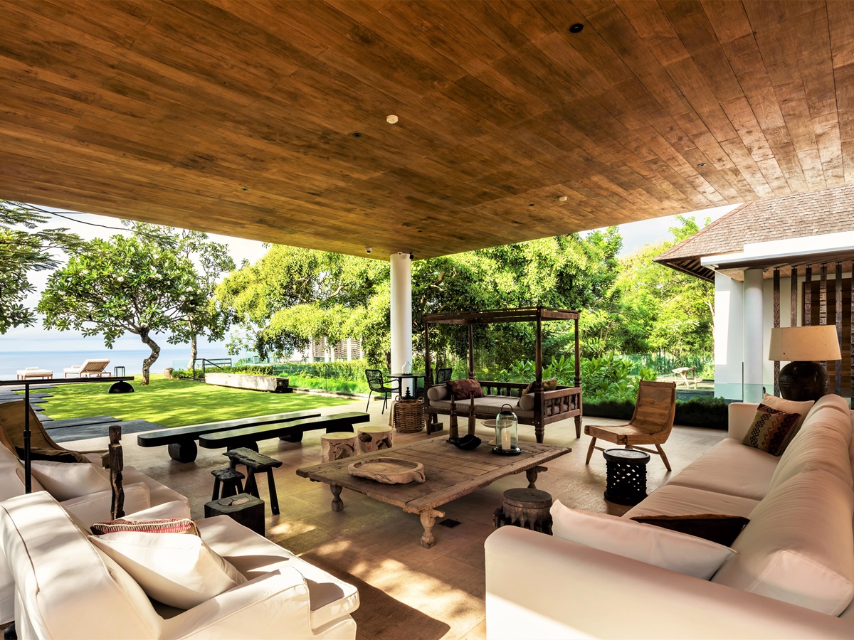 Outside seating area with wooden furniture and sofas at Uluwatu Estate, Bali