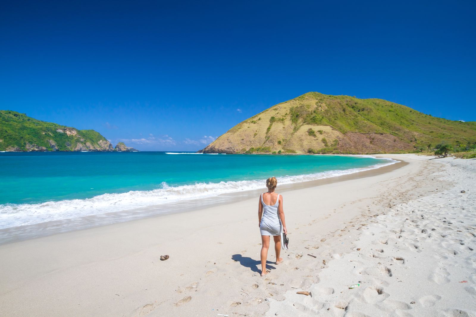 Lady walking along a white sand beach in Lombok, Indonesia