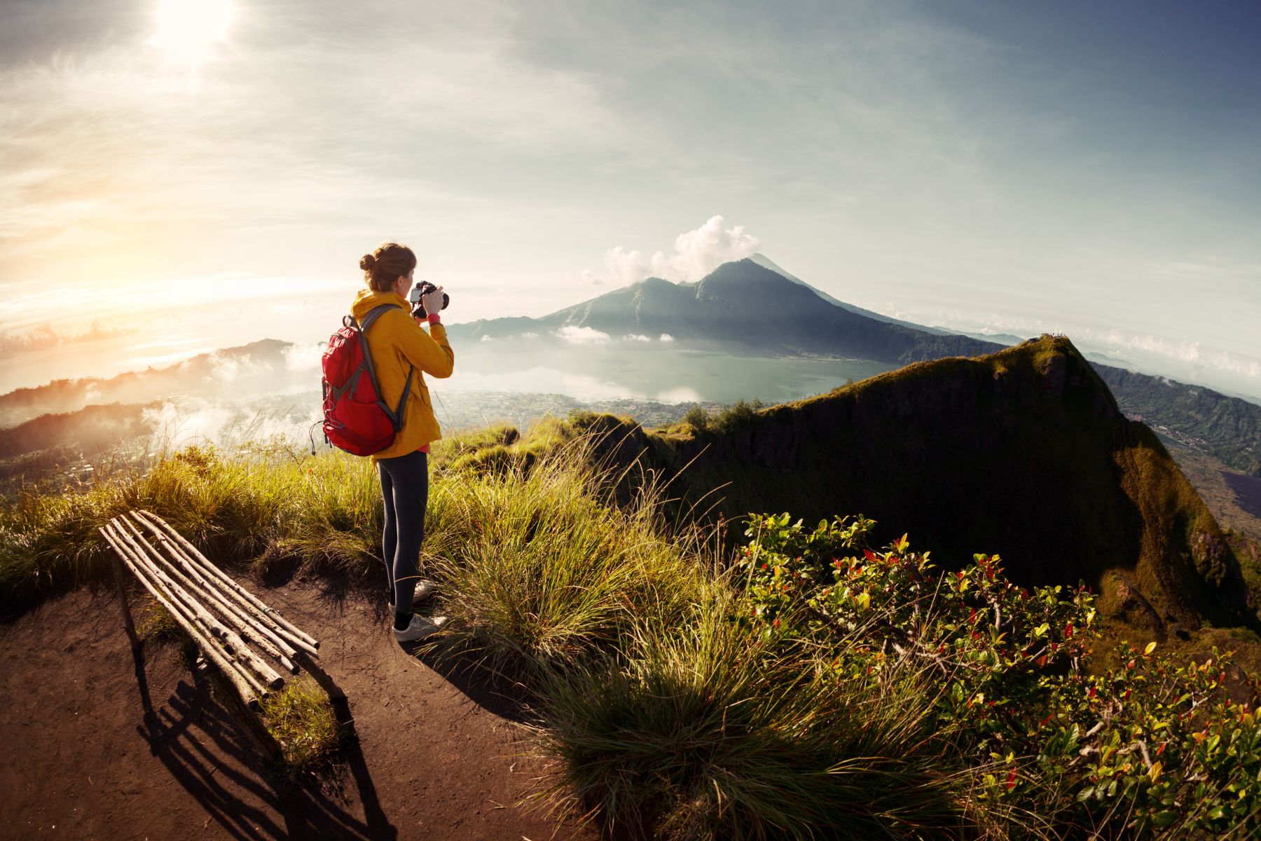 A hiker photographing the peak of Mount Batur at sunrise in Indonesia