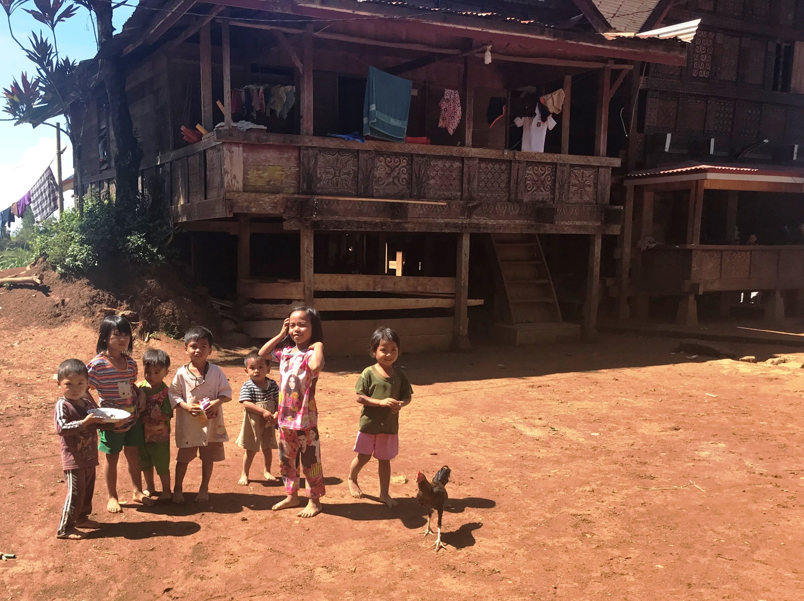 Group of young children in front of a wooden house
