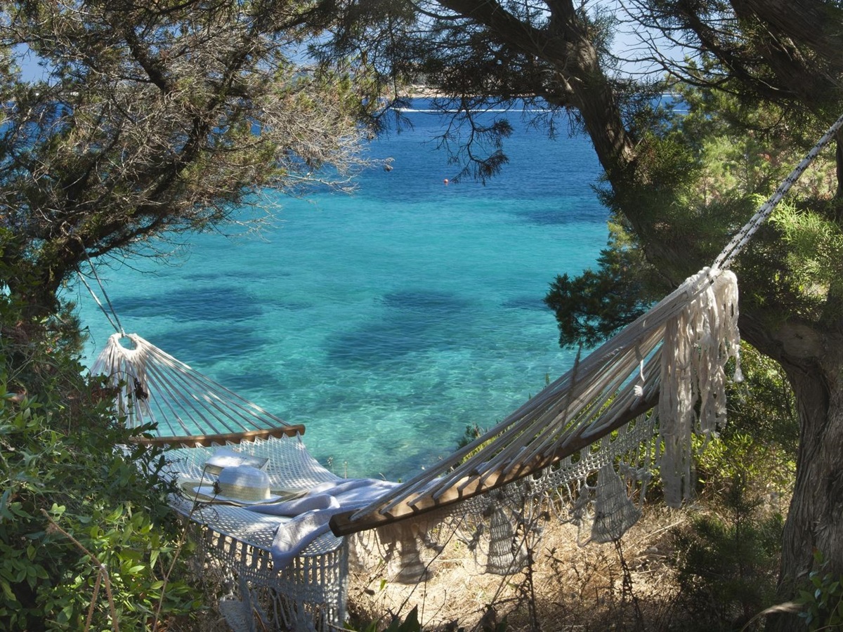 A hammock hidden between trees overlooking the turquoise waters of the Mediterranean at luxury hotel Capo d'Orso on Sardinia, Italy