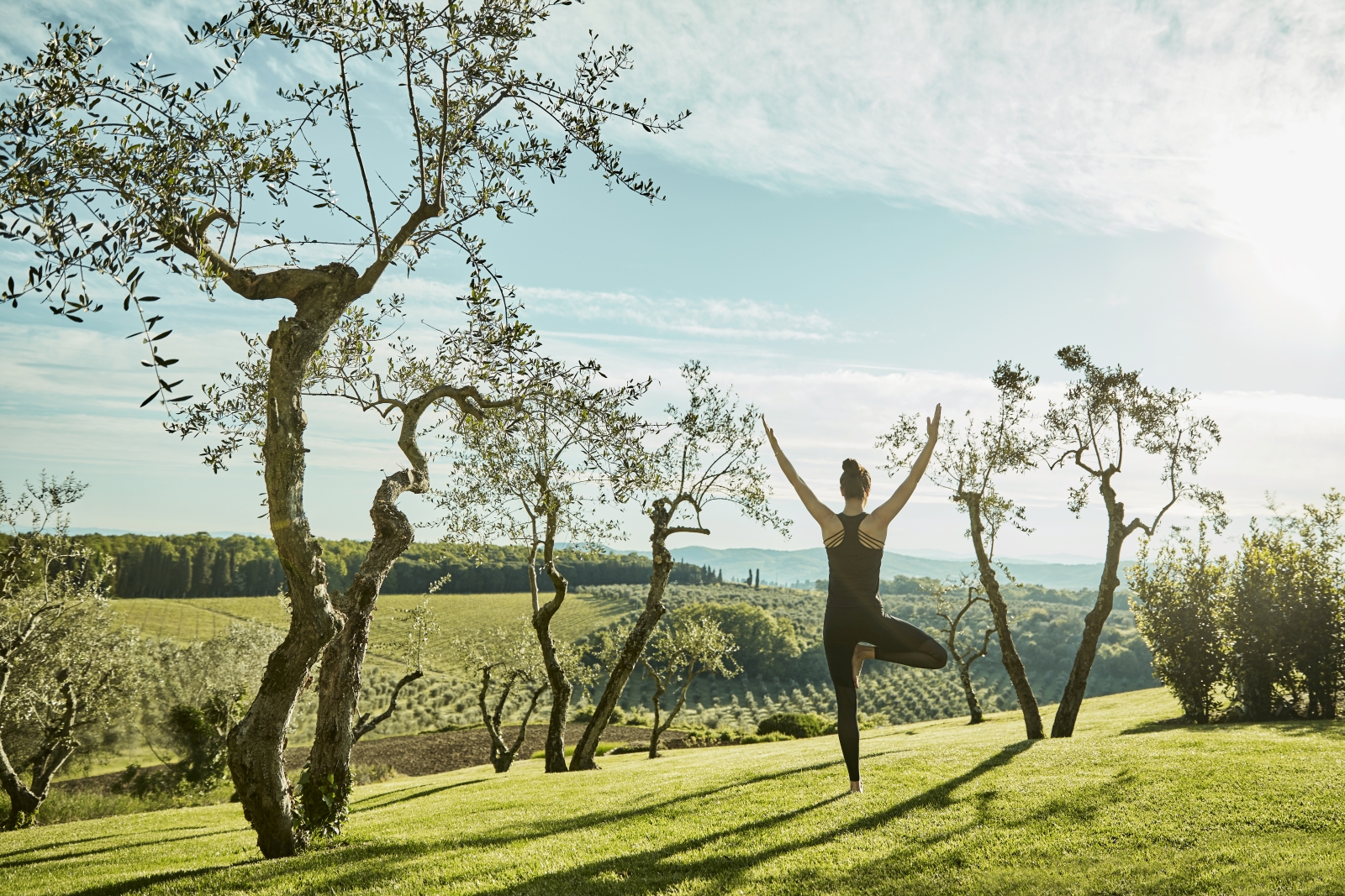Guest practising yoga in the gardens of luxury resort COMO Castello del Nero in Italy