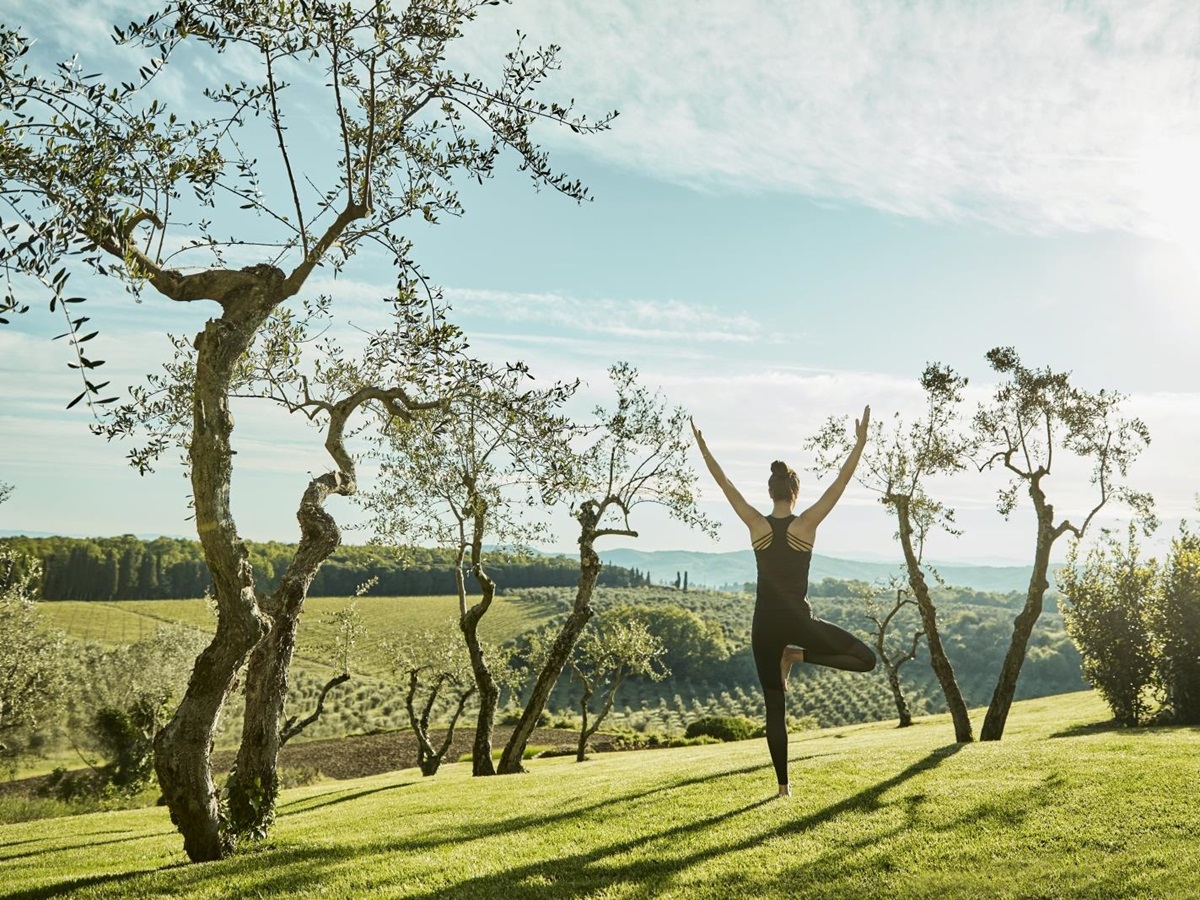 Guest practising yoga in the gardens of luxury resort COMO Castello del Nero in Italy