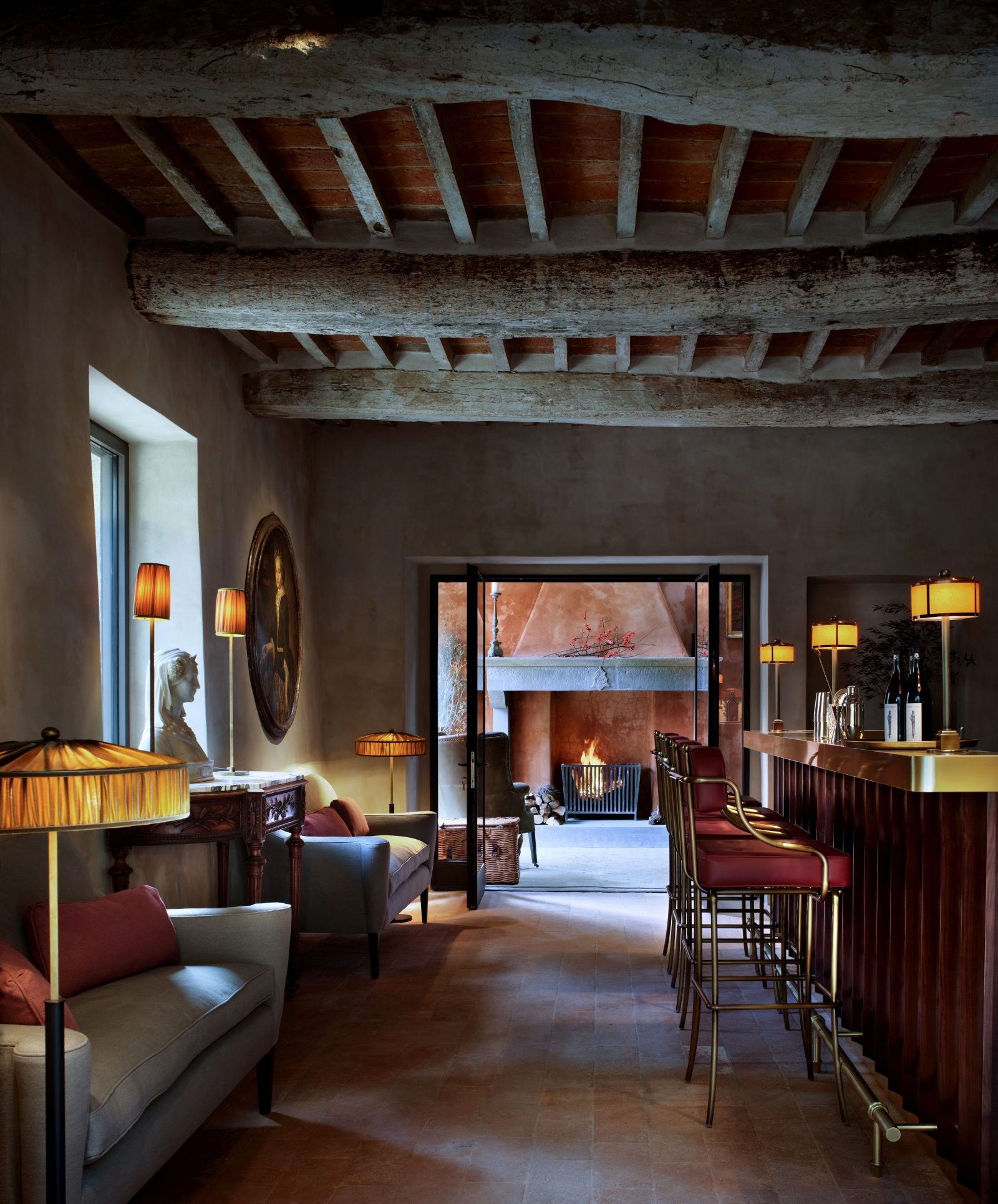 Bar at luxury hotel Castello di Reschio in Umbria, Italy, with exposed wooden beam ceiling and elegant red and gold accents
