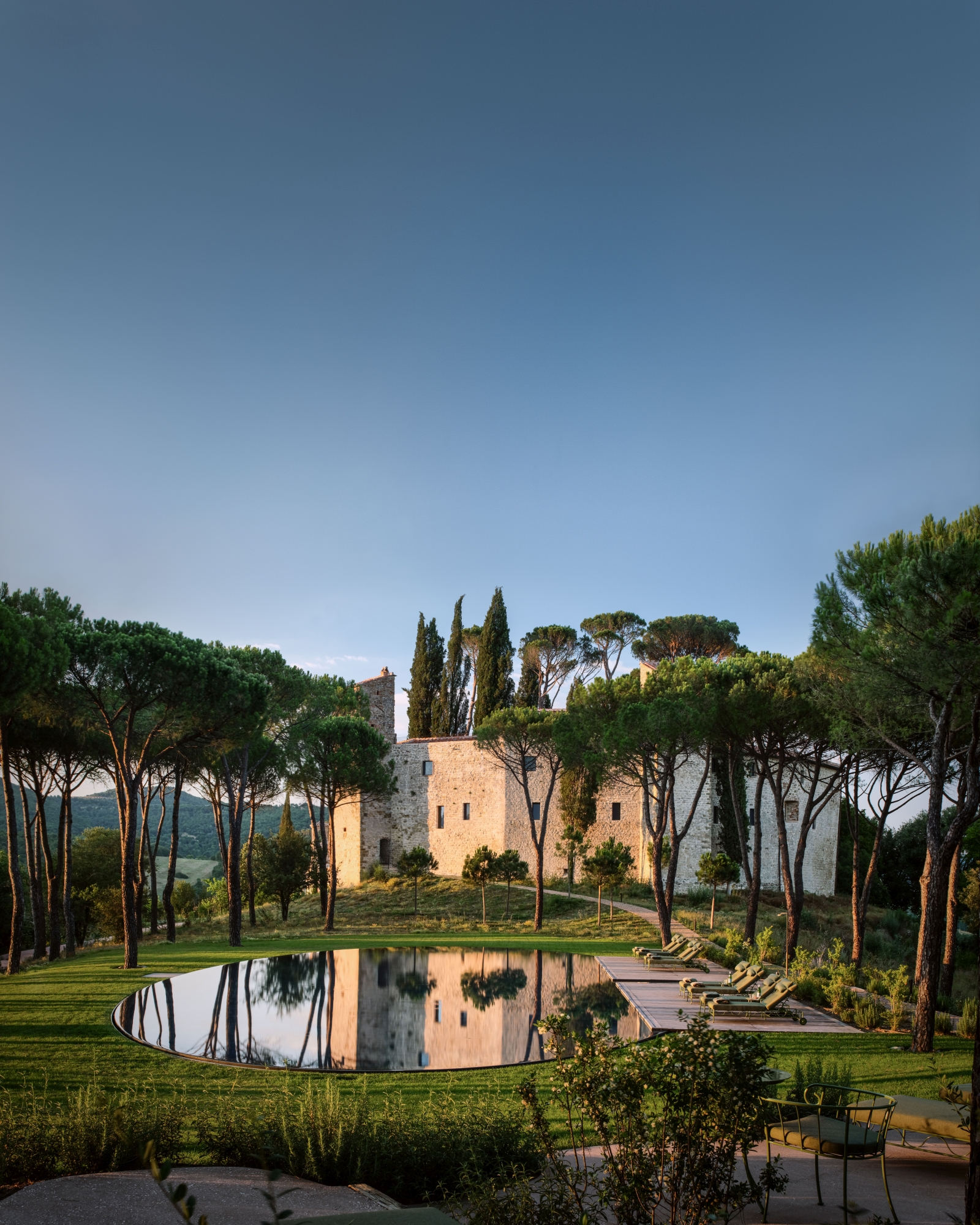 View of luxury hotel Castello di Reschio in Umbria, Italy and pool, surrounded by acacias