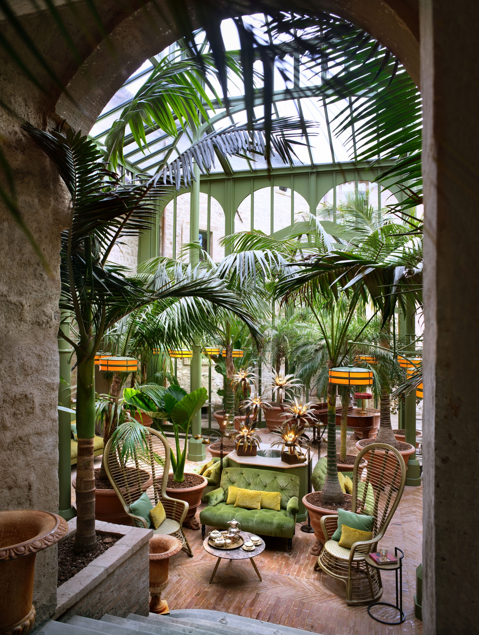 Seating area in the conservatory at luxury hotel Castello di Reschio in Umbria, Italy, with palms and other tropical plants