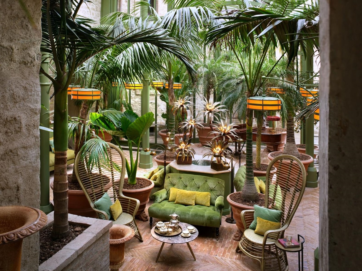 Seating area in the conservatory at luxury hotel Castello di Reschio in Umbria, Italy, with palms and other tropical plants