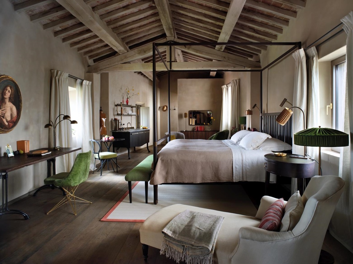 Elegantly rustic bedroom at luxury hotel Castello di Reschio in Umbria, Italy, with four poster bed, desk space and large windows