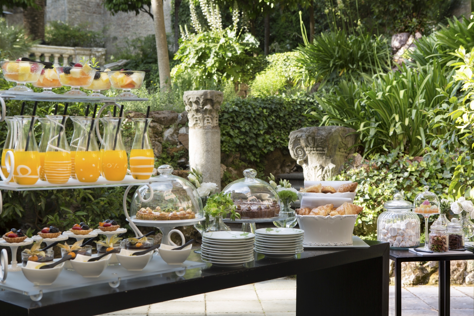 Afternoon tea in the gardens, with fresh juices, cakes, fruit and pastry at Hotel de Russie, luxury hotel in Rome, Italy