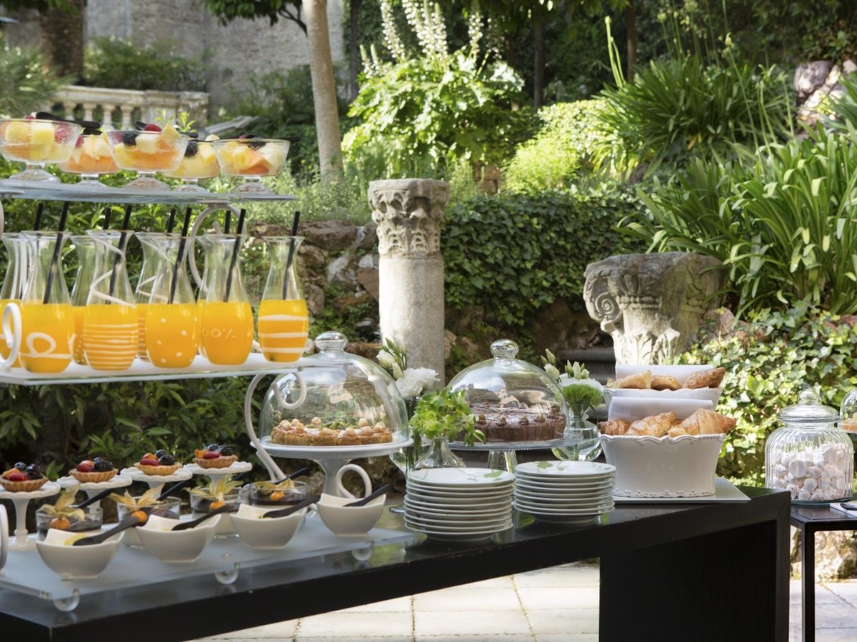 Afternoon tea in the gardens, with fresh juices, cakes, fruit and pastry at Hotel de Russie, luxury hotel in Rome, Italy
