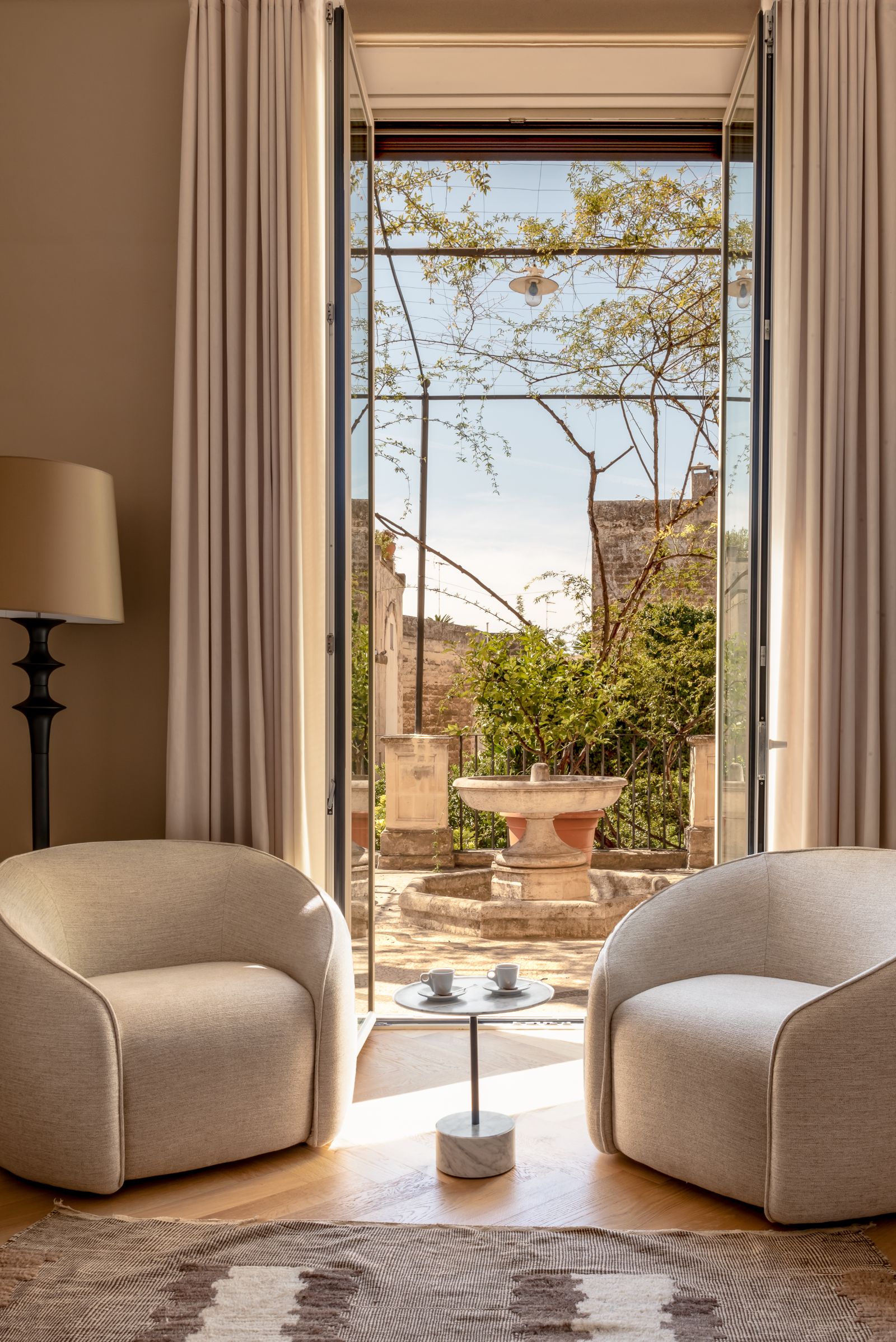 Two comfortable chairs in front of a door to a terrace in a Classic Suite at luxury hotel Palazzo Bozzi Corso in Lecce, Italy