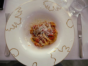 A white dish with gold decorative lines and wide rim with pasta in the middle