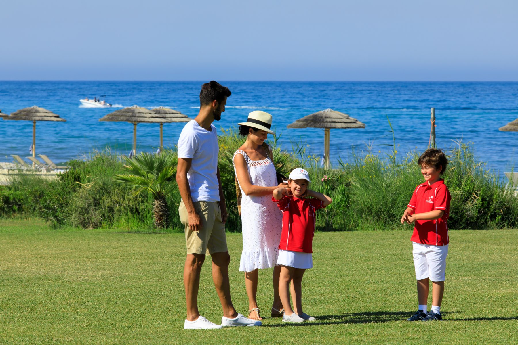 Family in gardens near the beach, wiht the sea in the background, at Rocco Forte Verdura Resort in Sicily