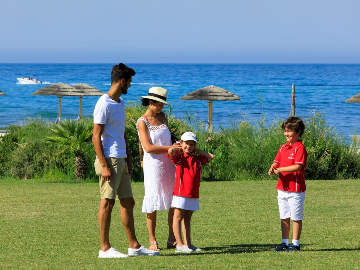 Family in gardens near the beach, wiht the sea in the background, at Rocco Forte Verdura Resort in Sicily