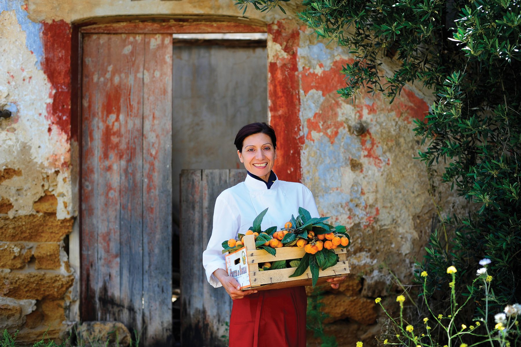 Staff member carrying a crate of loquats at Rocco Forte Verdura Resort in Sicily