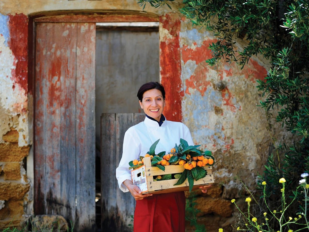 Staff member carrying a crate of loquats at Rocco Forte Verdura Resort in Sicily