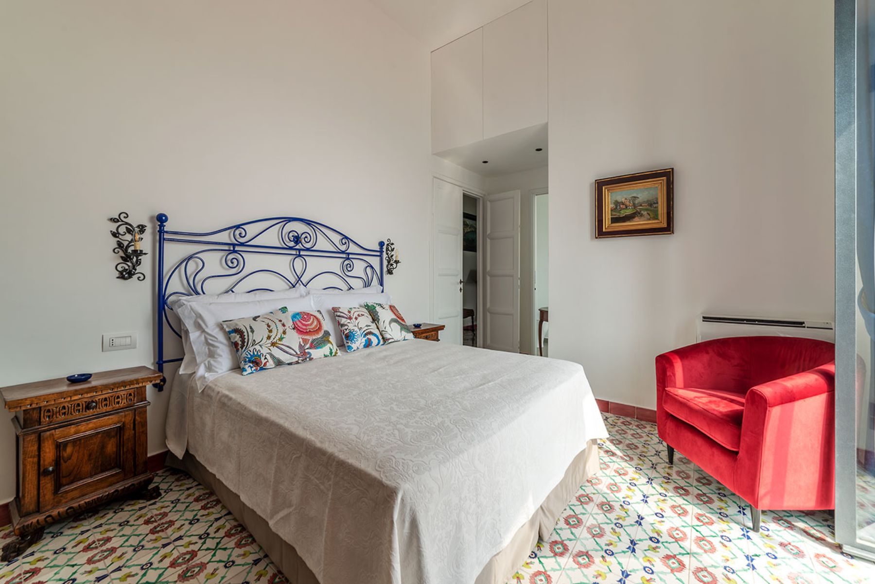Bedroom with double bed tiled floors and red armchair at Castello Sul Mare in Amalfi