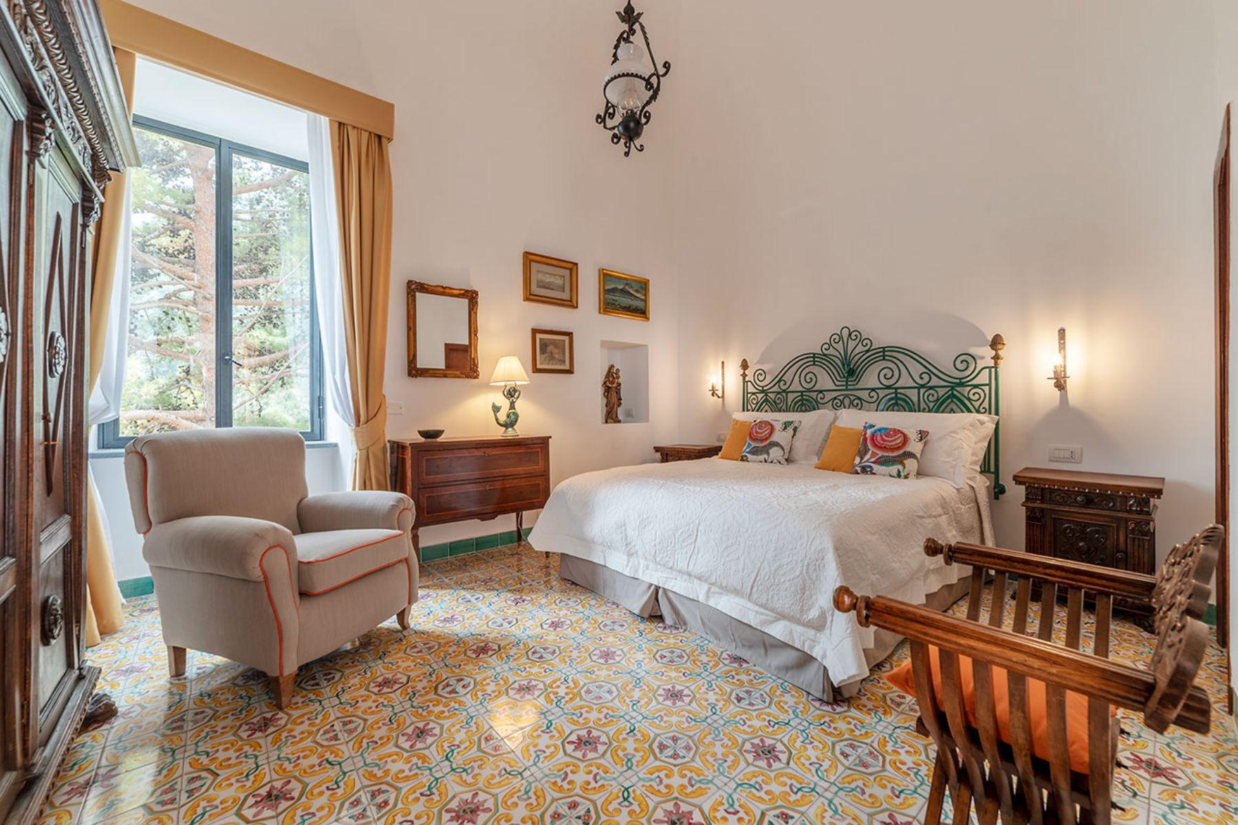 Large bedroom with double bed and tiled floors and armchair at Castello Sul Mare in Amalfi