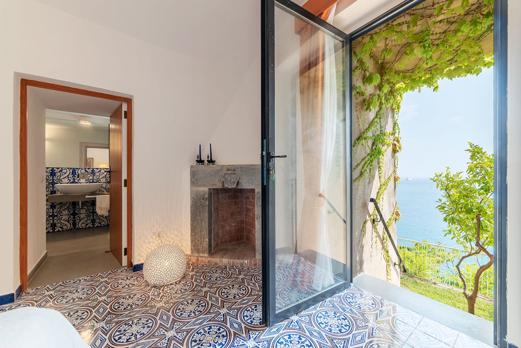 Ground floor bedroom with fireplace and and large glass door at Castello Sul Mare in Amalfi